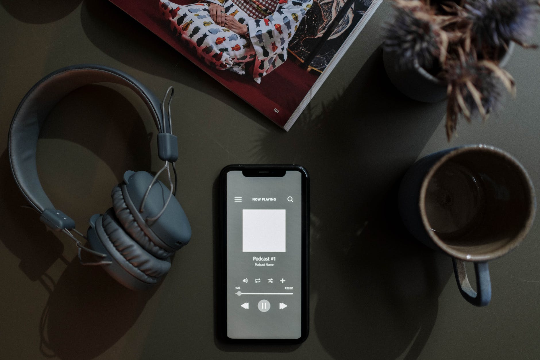 overhead shot of a cellphone between a mug and headphones