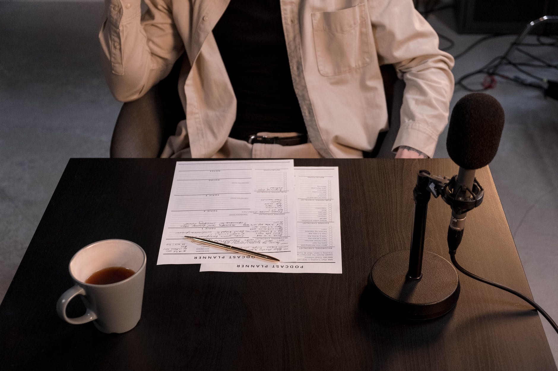 person in white dress shirt sitting beside brown wooden table with white ceramic mug and black